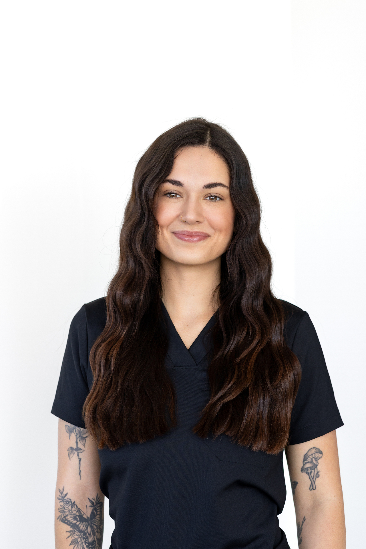 Gena Cockrell, KC Aesthetician — soft-smile portrait in black scrubs